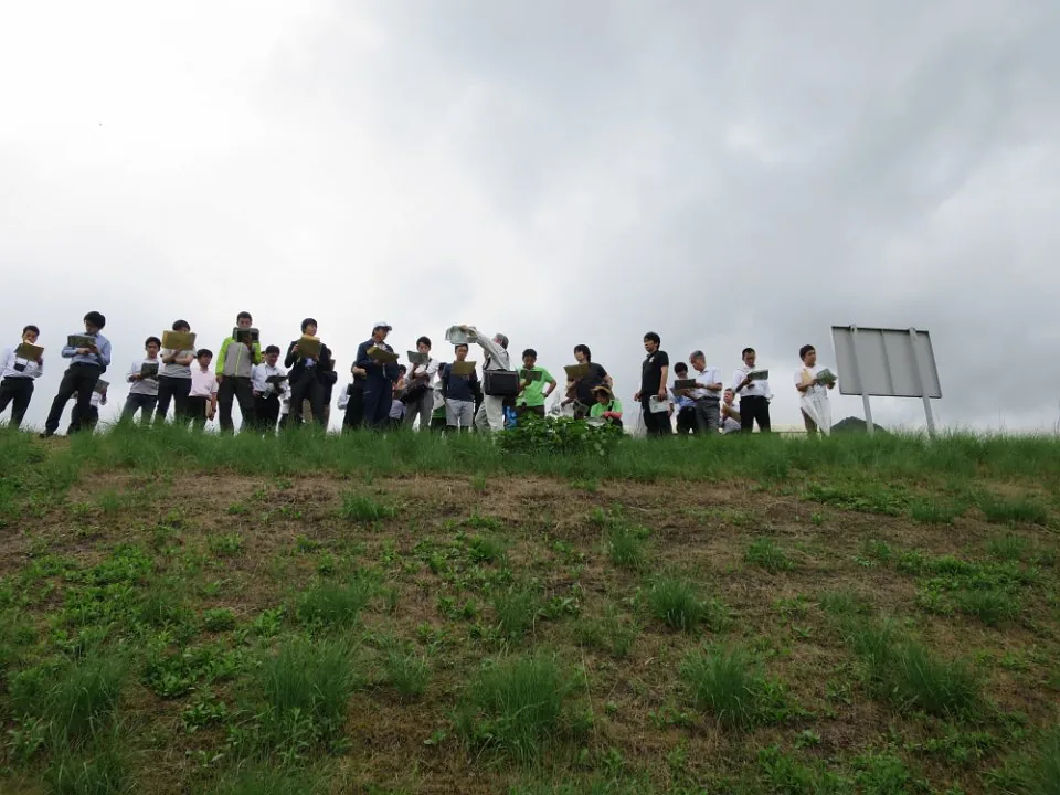 堤防の上で川を眺める講習会参加者