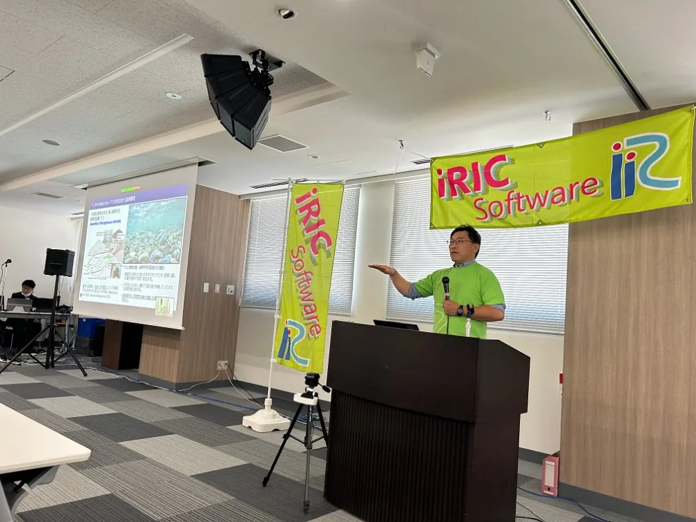 iRIC の横断幕の前で講演する様子